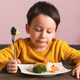 Young boy looking disgusted at plate of vegetables